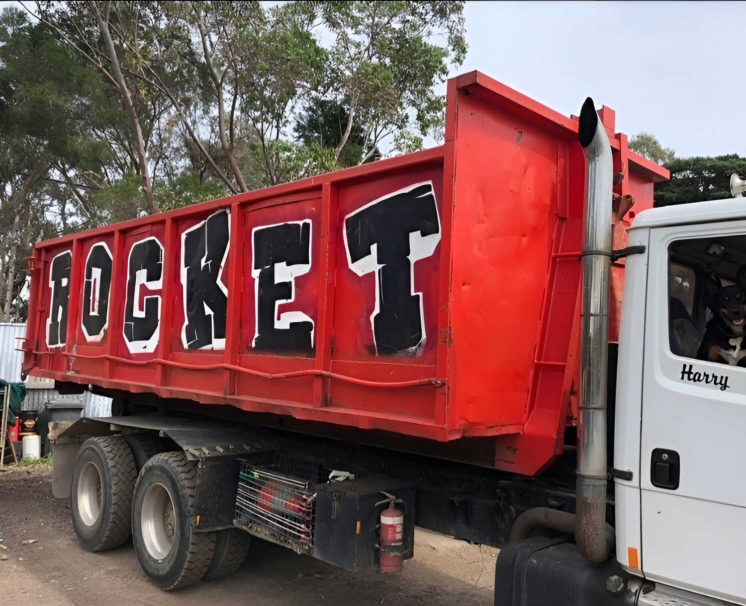 7 Red bin painted with ROCKET in big black letters on a hook-lift truck