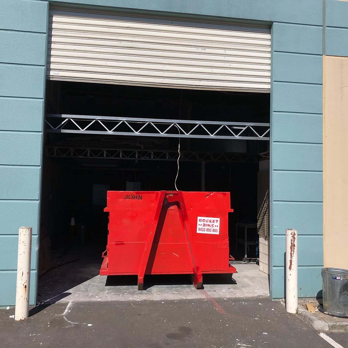 Red walk-in bin in the open roller door of a warehouse unit
