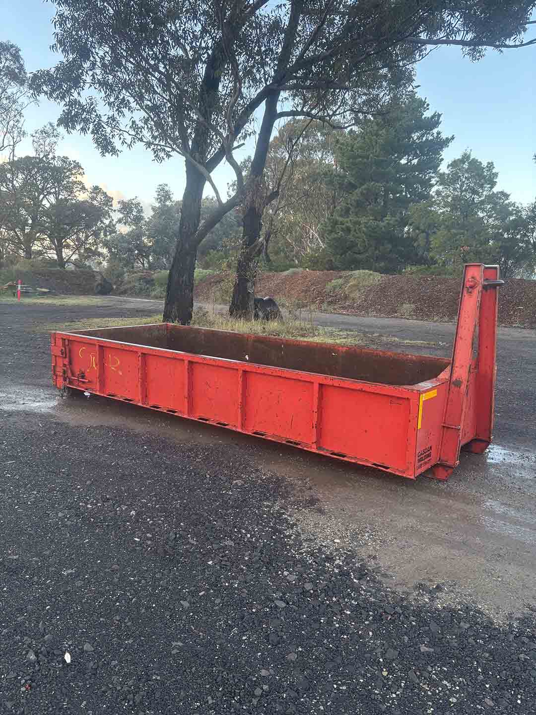 s1a Red 6m³ walk-in bin on a gravel yard under gum trees