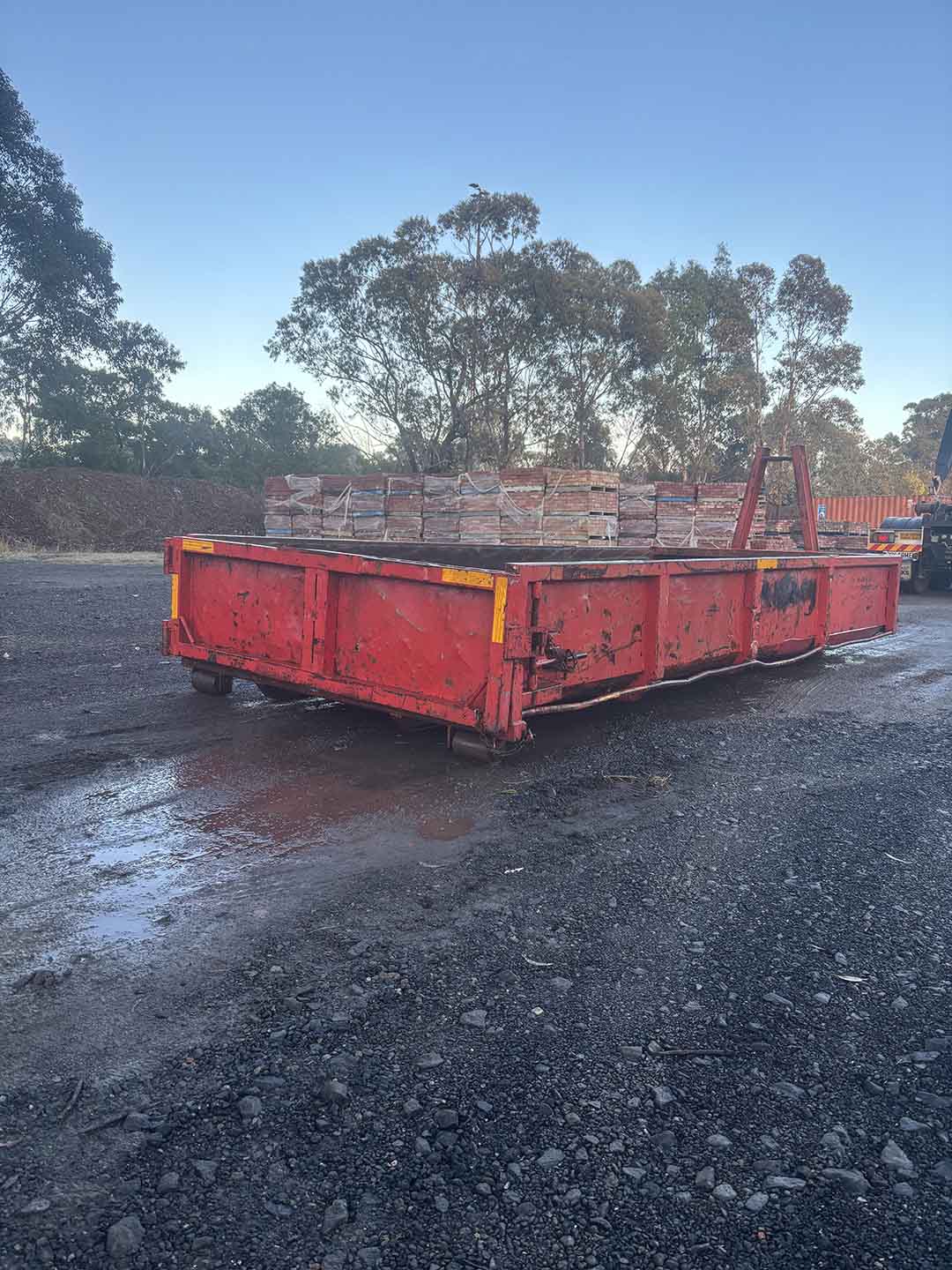 s2c Red 8m³ walk-in bin in a yard with pallets of bricks behind