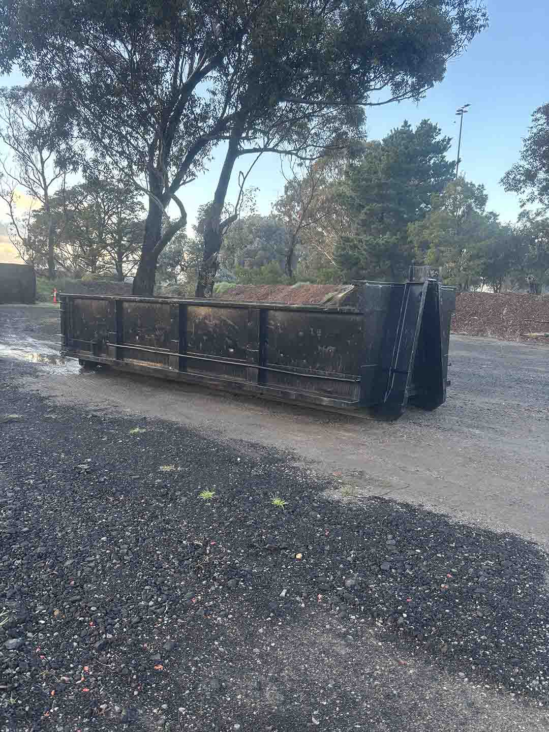 s5a Black walk-in bin on a gravel yard under gum trees