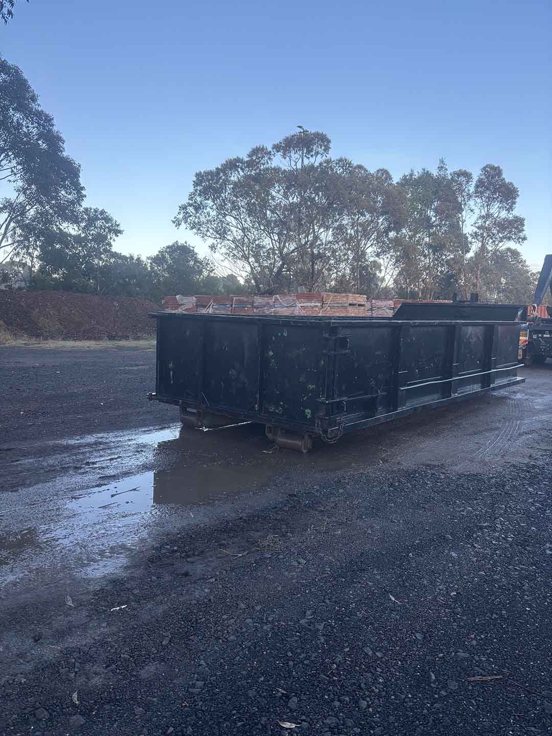 s5b Black walk-in bin in a wet yard, side view