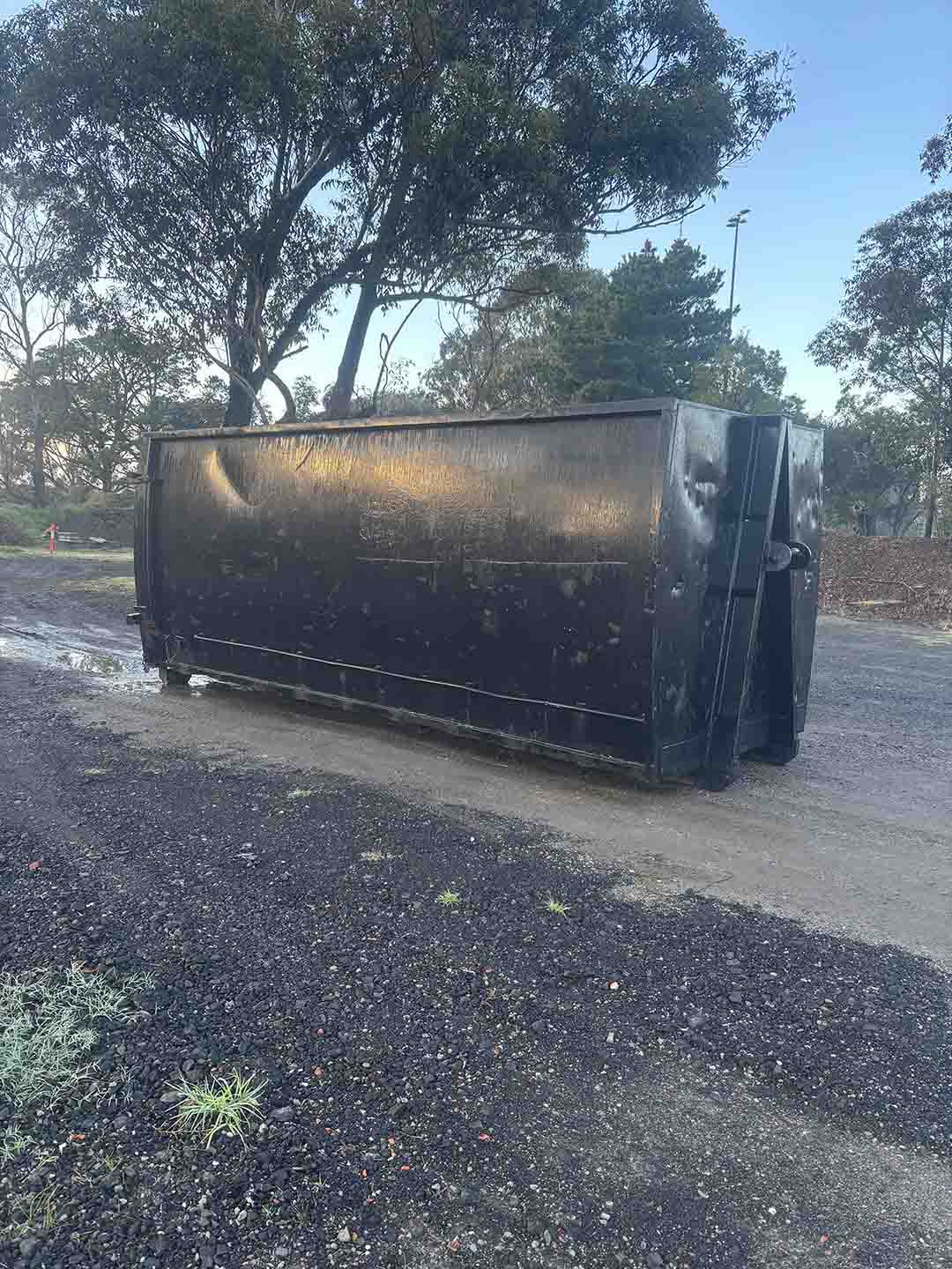 s7a Black 30m³ walk-in bin on a gravel yard under gum trees