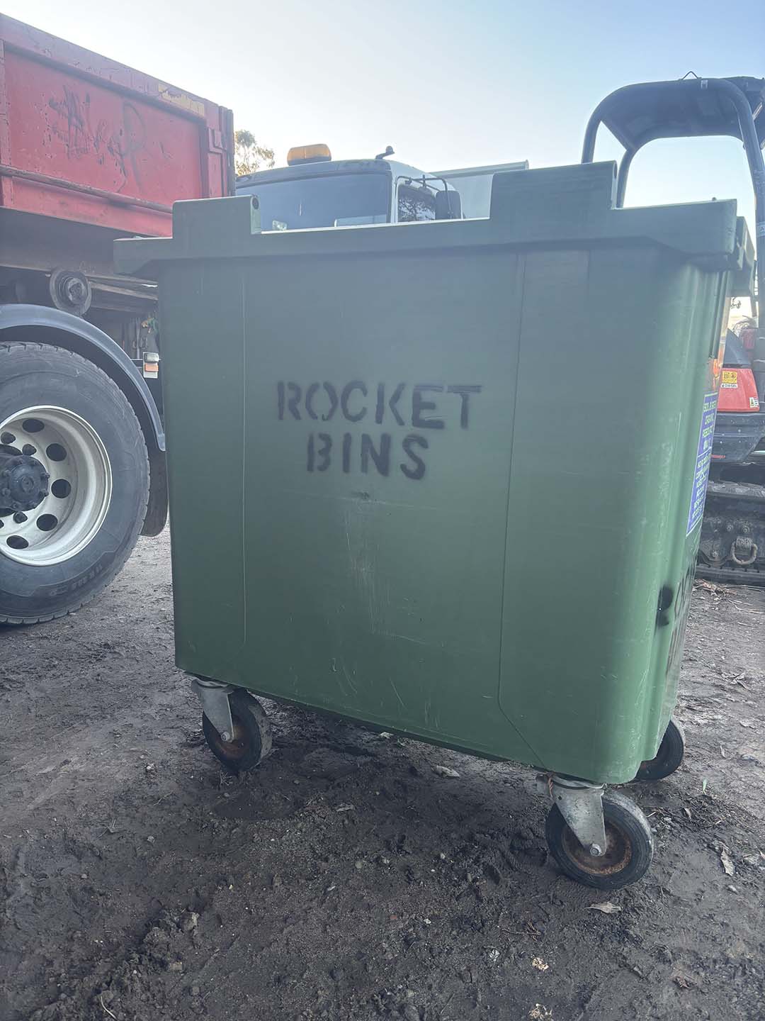 s8c Green 660L wheelie bin stencilled ROCKET BINS beside a truck